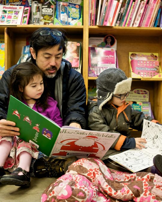 A family sitting on the floor reading children’s books at Powell’s City of Books.