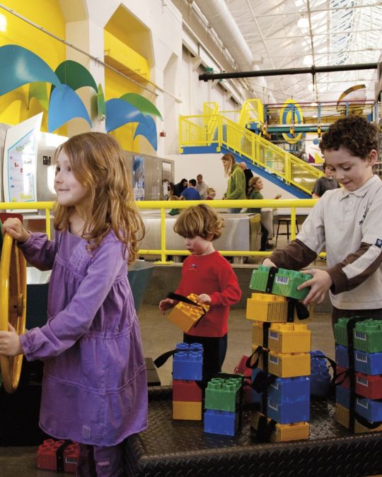 Three kids get hands-on learning with colorful interactive exhibits at OMSI.