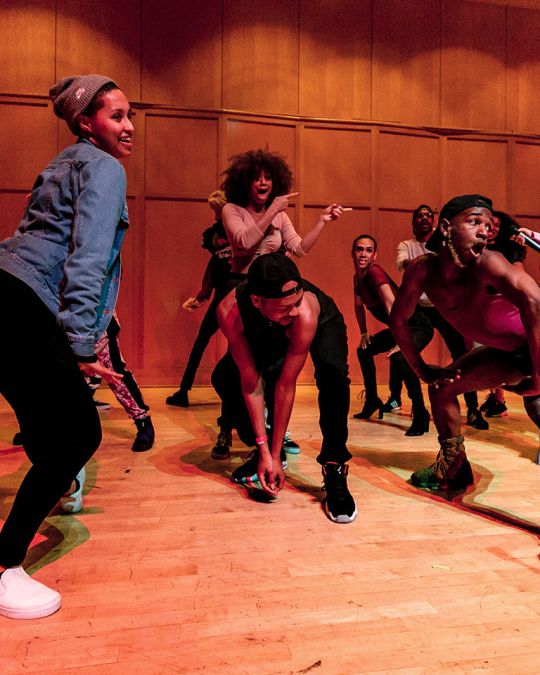 A group of Black people dancing together in a school classroom