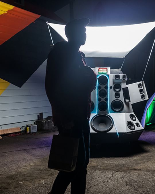 a person standing in front of a speaker display and a painted wall