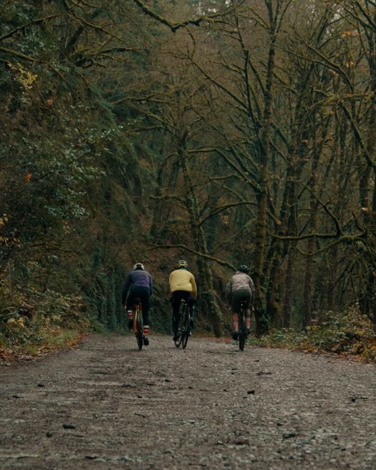 three cyclists ride on a muddy gravel path in Forest Park