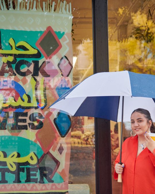 a woman holding an umbrella and coffee cup
