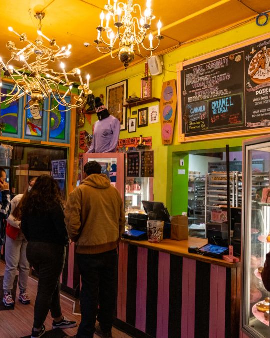 people stand in a lobby decorated with art, colors, and menus on the wall
