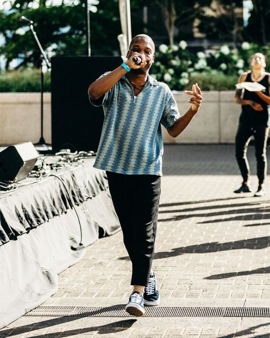 a person sings into a microphone in front of a small crowd