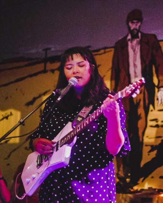 Woman sings with guitar