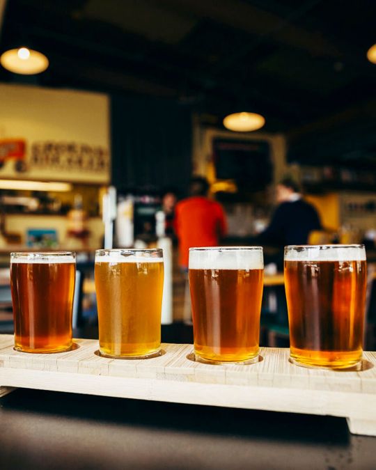 a tasting flight of draft beers next to an open bottle