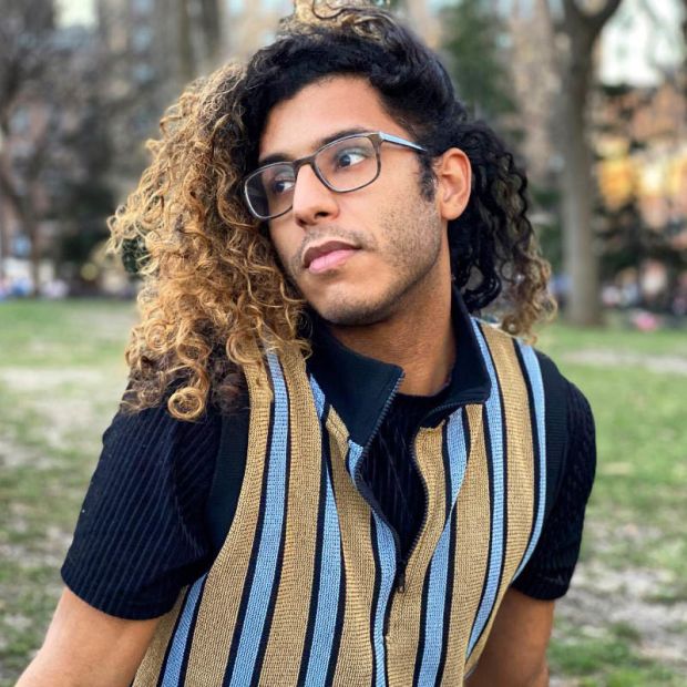 close up of a person sitting in a park, looking off to the side