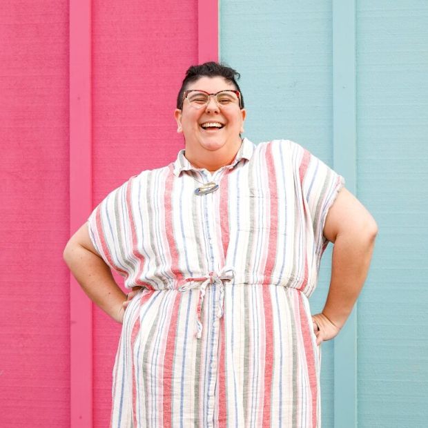 image of a person standing with their hands on their sides, in front of a pink and blue wall