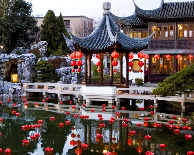 red lanterns float in water in front of a Chinese-style building