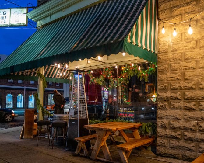 store front lit at night with outdoor benches