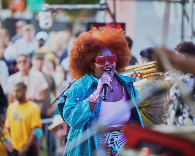 a colorfully-dressed performer sings on stage in front of musicians