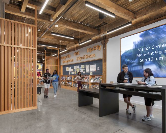 People walking the entryway at the Portland Visitor Center, reading brochures and socializing.