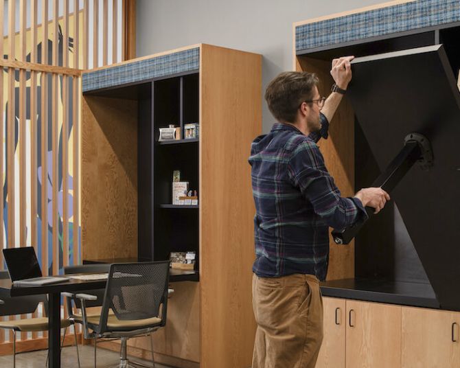Person folding up a stowaway desk at the Portland Visitor Center.