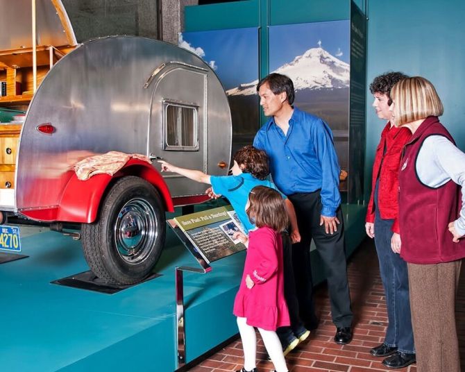 a family looking at a camping vehicle on display at the Oregon History Museum