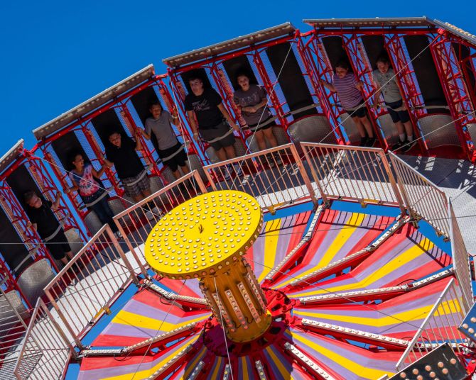 people strapped in and standing on a spinning amusement ride