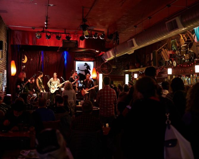 a band on a stage plays in front of a dimly lit crowd