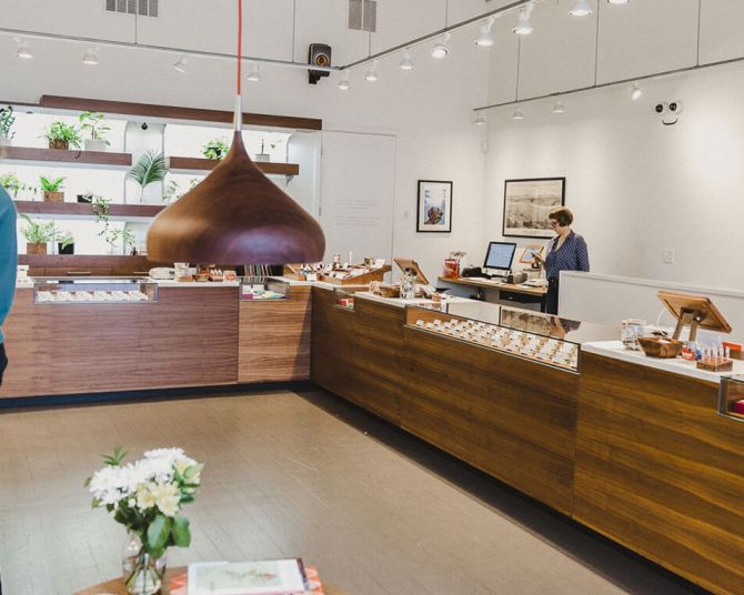 the bright interior of a modern cannabis shop lined with plants and display cases