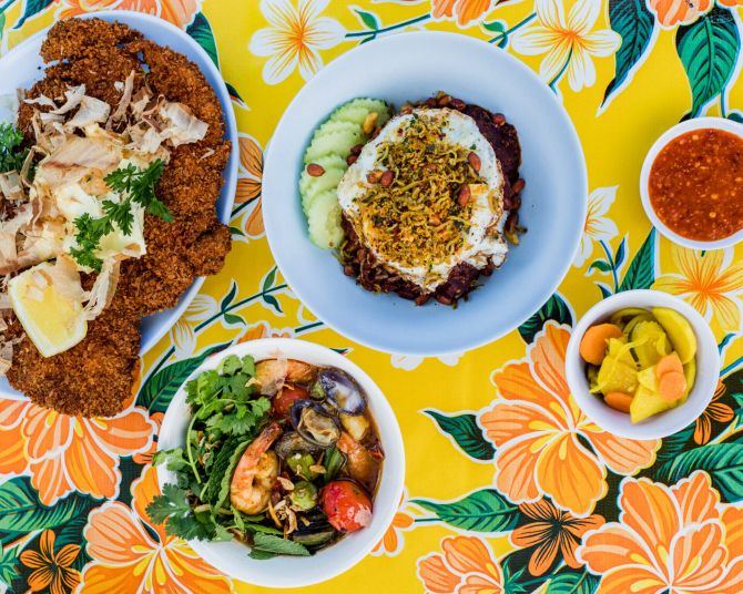 Southeast Asian food on plates against a vibrant table cloth.