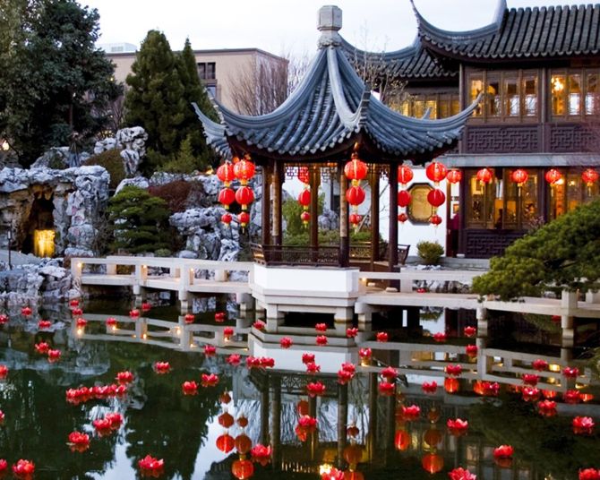 red lanterns float in water in front of a Chinese-style building