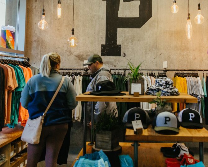 two people browse through racks of clothing at a shop