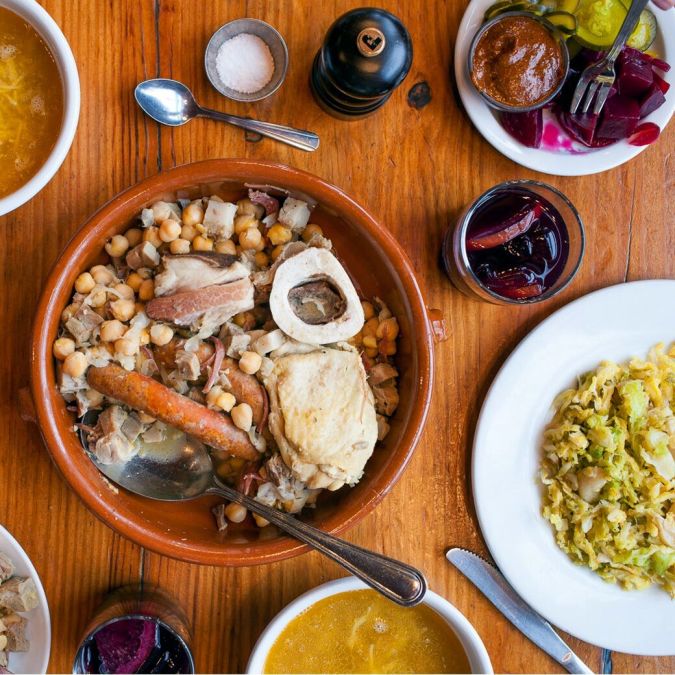 An array of beautiful Spanish foods at Toro Bravo, bright yellow soups and red clay pots of chickpeas, sausage and chicken.