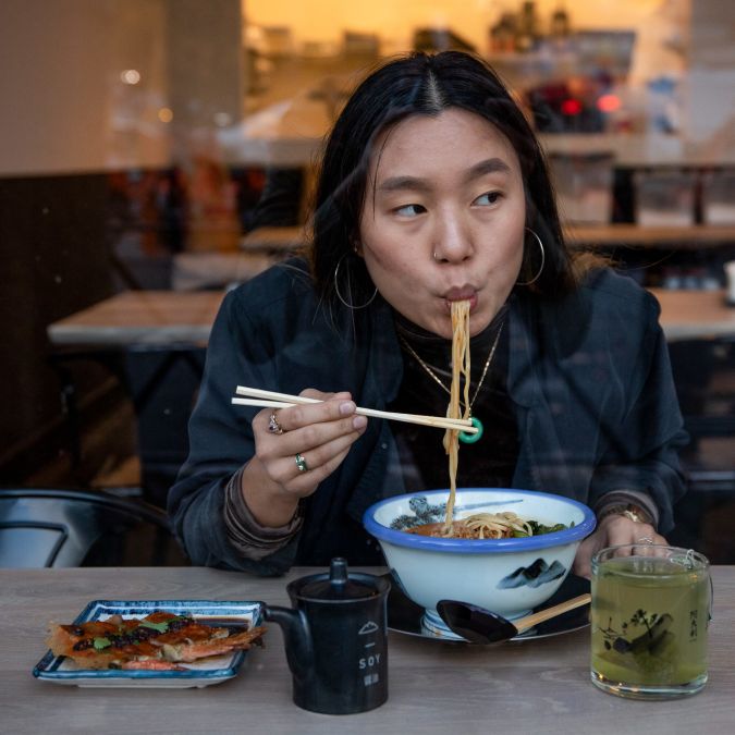 A person slurps ramen noodles
