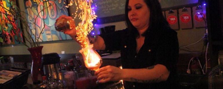 a bartender making a flaming drink behind the bar at Local Lounge