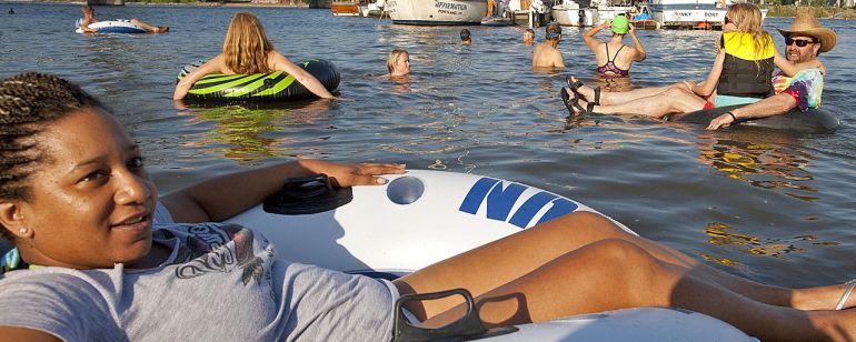 a group of people sitting in inner tubes and swimming in a river