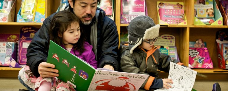 A family sitting on the floor reading children’s books at Powell’s City of Books.