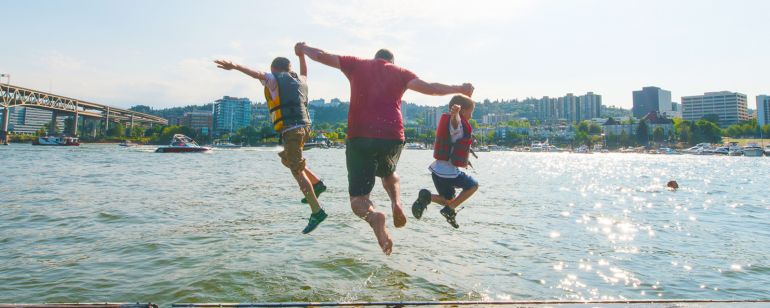 three people mid-jump into a river