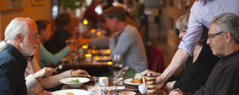 a server giving a table of diners an espresso at a restaurant