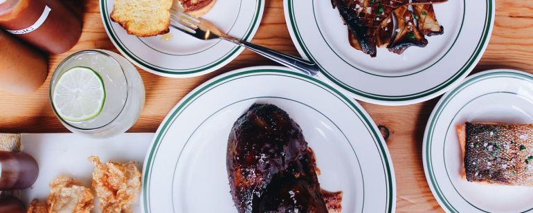 two plates of BBQ and some side dishes