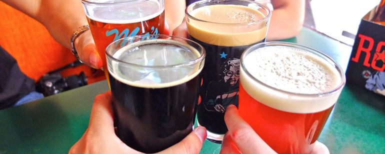 Four hands with four beers toast to world-class beer and spirits at Rogue Distillery and Public House.