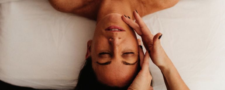 a woman receiving a facial massage at Blooming Moon Spa