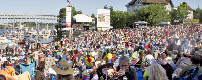 a massive crowd of people enjoying music on the waterfront