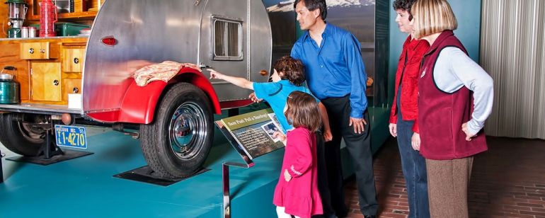 a family looking at a camping vehicle on display at the Oregon History Museum
