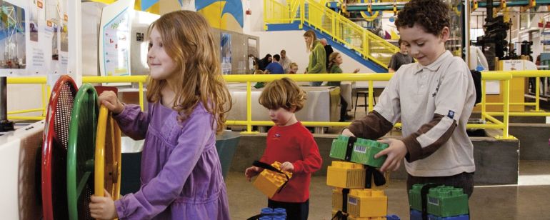 Three kids get hands-on learning with colorful interactive exhibits at OMSI.