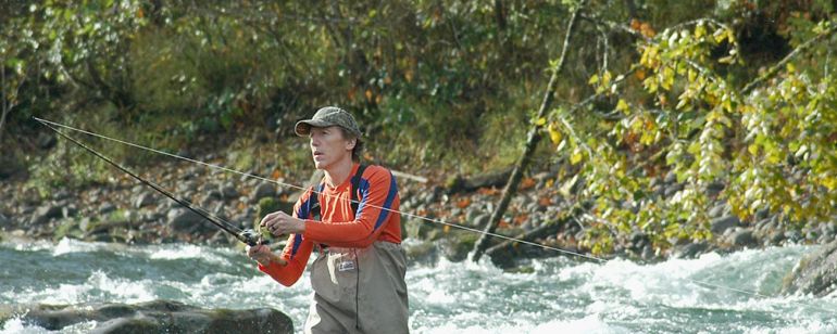 a fisherman flyfishing in a river