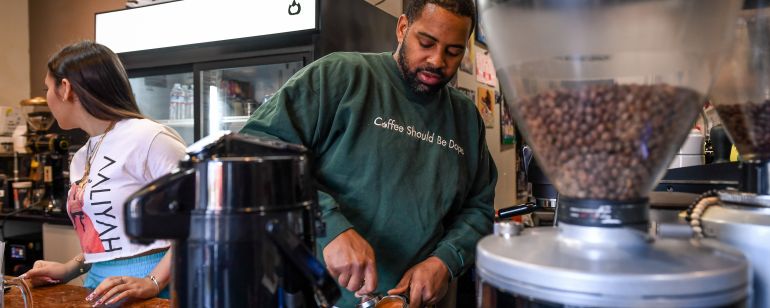 man and woman behind counter preparing espresso at a coffee shop