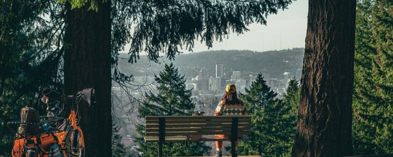a person sits on a bench overlooking Portland at Mount Tabor Park