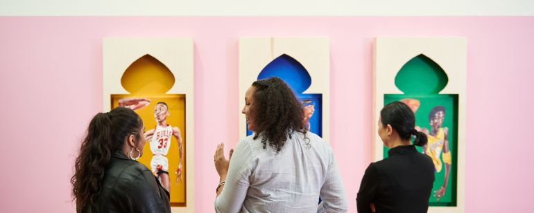 three woman in front of an art mural