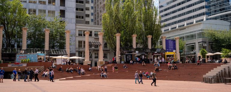 people sitting, walking in brick plaza with white columns