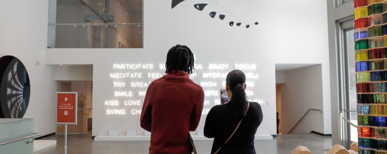 two people stand looking at a contemporary art installation in an art museum