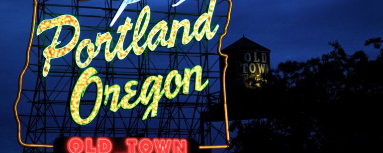 a neon light sign reading \"portland oregon old town\" with a deer leaping over the words