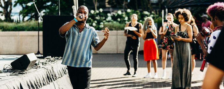 a person sings into a microphone in front of a small crowd