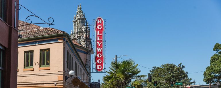 people walking on the sidewalk under a vintage Hollywood Theater sign