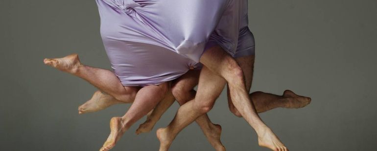 people covered in fabric with only legs showing in an artistic dance performance