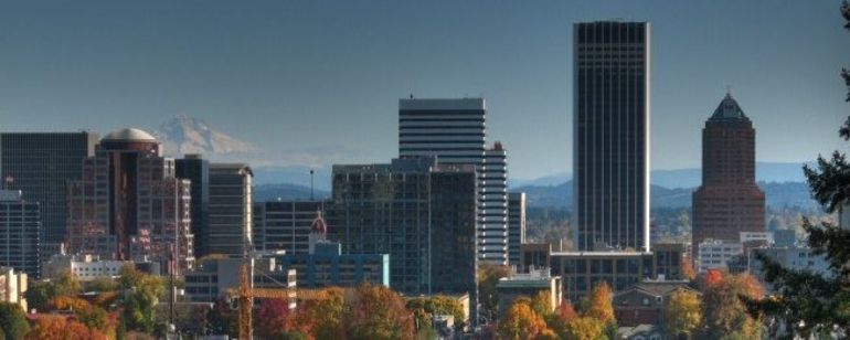 A view of downtown with its trees a fiery autumn orange with a snow capped Mt. Hood in the background.