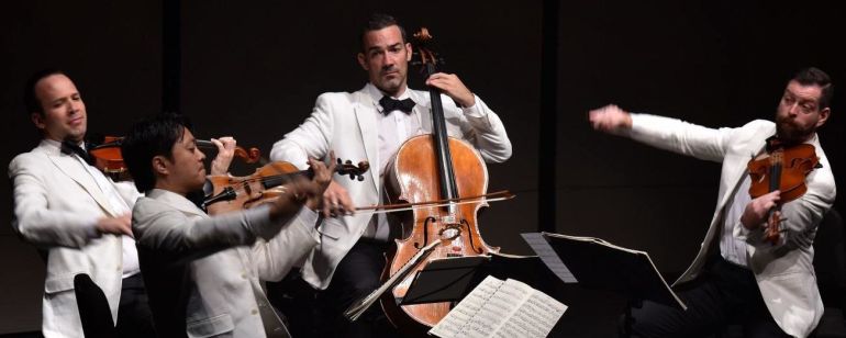 a quartet of string musicians wearing white tuxedos