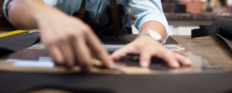 a man at a workbench cutting materials at Orox leather